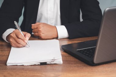 İmza konsepti. Ofisteki masada otururken kira kontratı ya da anlaşma imzalayan takım elbiseli bir işadamı. Yakın plan fotoğraf. İş ve belge yönetimi kavramı