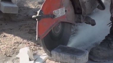 Bir işçi istenen büyüklükte bir tuğlayı dairesel testere ile testereyle keser.