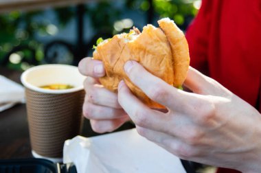 Elin ısırılmış bir hamburgeri tutuyor.