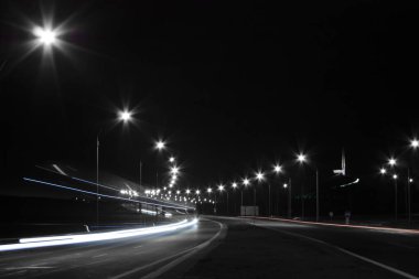 Gece yarısı sokak lambalarıyla aydınlanan bir otobanın yatay manzara fotoğrafı. 