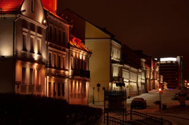 Yatay şehir manzarası. Şehrin eski bölümündeki binaların cepheleriyle birlikte üç çeyrek manzara. Boş bir sokakta gece aydınlatması.