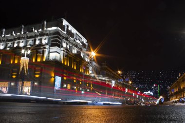 Yatay kavramsal gece fotoğrafı ve bir şehrin kavşak noktasında hızla geçen bir arabanın ardından bir ışık izi.