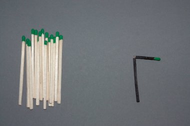 Horizontal conceptual subject photo with group of white matches and a single broken black match symbolizing the oppression of a minority by the majority because of differences clipart