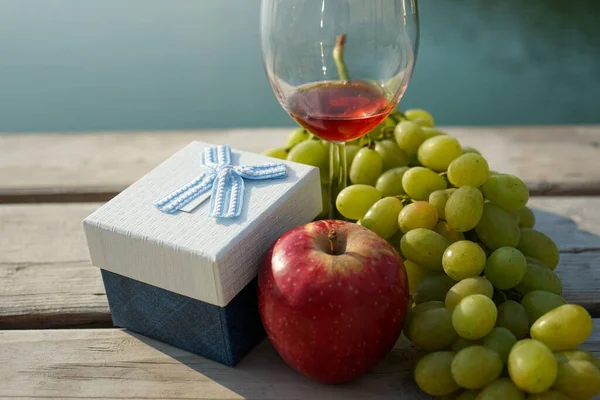 fruit and gift box on the pier and a glass of wine