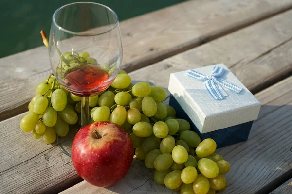 fruit and gift box on the pier and a glass of wine