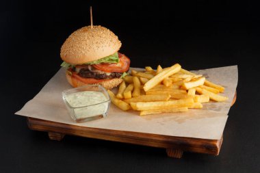 Koyu arkaplanı olan bir panoda iştah açıcı burger.