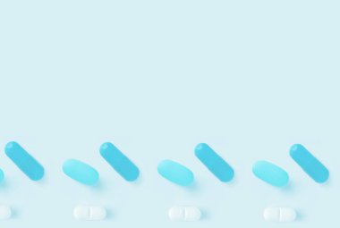 Hafif gölgeli açık mavi arka planda mavi ve beyaz hapların minimalist düzenlenmesi ve kopyalama alanı.