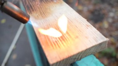 Geleneksel Japon tekniğini kullanan profesyonel bir marangoz. Gaz ocağıyla odun yakmak. Diy işlemi. Gaz ocağı yangını başlatıyor. arkaplan için ışıklandırma tahtası