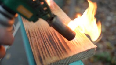 Geleneksel Japon tekniğini kullanan profesyonel bir marangoz. Gaz ocağıyla odun yakmak. Diy işlemi. Gaz ocağı yangını başlatıyor. arkaplan için ışıklandırma tahtası