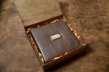 Tahta bir kutuda, deri bir kapakta, ormanlık bir arka planda hediye fotoğraf kitabı. Klasik fotoğraf albümü. Bir kişinin hayatının birkaç resmi..