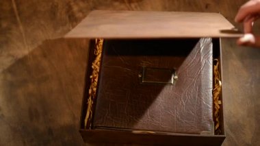 Kız deri bir kapakta, tahta bir kutunun içinde, ormanlık bir zeminde hediye fotoğrafı çekiyor. Klasik fotoğraf albümü. Bir kişinin hayatının birkaç resmi..