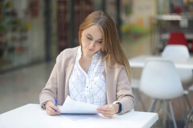 Belgeleri okumak, İşkadını Masa başı, Evrak işleri. Uzun saçlı bayan alışveriş merkezinin kafesinde otururken kontratı kontrol ediyor. Kadın gülümsüyor. işgücü bağlantısı gibi