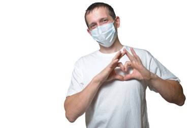 Maskeli ve beyaz tişörtlü mutlu bir adam sevgilisine Sevgililer Günü hediyesi olarak elinden bir kalp veriyor. tatil konsepti pandemik modda. Doktor kalp bağışı yapıyor.