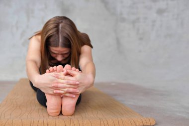 Paschimottanasana yoga antremanı yapan çıplak bir kızın ayaklarına yaklaş. Öndeki kadın el ele tutuşarak poz veriyor. Esneklik kavramı