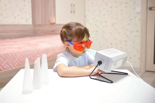 Kız, vücudu bakteri ve koronavirüs virüslerinden korumak için antibakteriyel ultraviyole kuvars lambasıyla burnunu temizliyor. Çocuk sağlığı hizmetleri