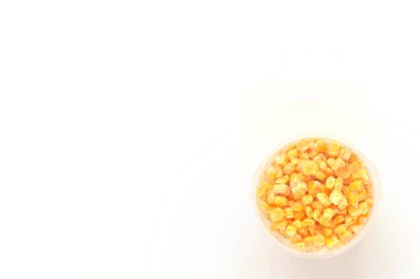 Plastik bir kabın içinde beyaz izole edilmiş arka planda donmuş mısır taneleri. Sebze koruma. Üst Manzara. Moda yemekler. Kış için sebze stokluyorum..