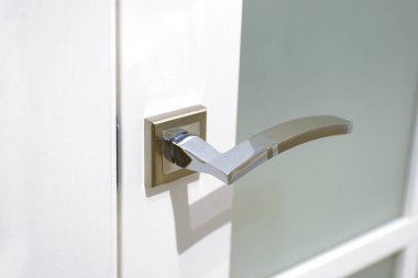 Beyaz kapıdaki paslanmaz çelik kapı kolu kapalı. Yakın plan. İç kapı için şık bir sapı var. Modern biçim