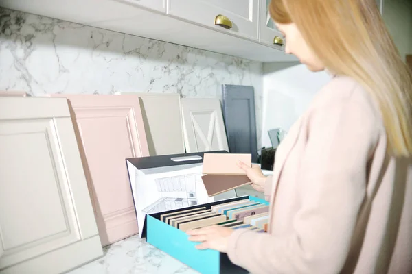 Kız tasarımcı kabine mobilyaları için ön cephe seçiyor. Mobilya endüstrisinde dekorasyon tahtaları. İç proje için malzeme ve renk örnekleri seçiliyor. Üst Görünüm Ev Geliştirme kavramı