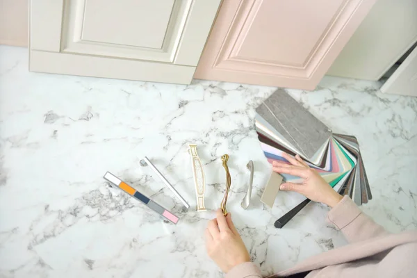 Ev geliştirme konsepti. Tasarımcı kız vitrindeki mobilyaların ön cephelerini ve kollarını seçiyor. Mobilya endüstrisinde dekorasyon tahtaları. Madde örnekleri seçiliyor.