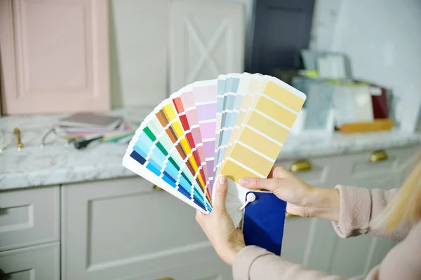 Ev geliştirme konsepti. Tasarımcı kız, mağazanın salonundaki renk paletine göre kabine mobilyaları için ön cephe ve kol seçer. Mobilya endüstrisini dekore ediyor.