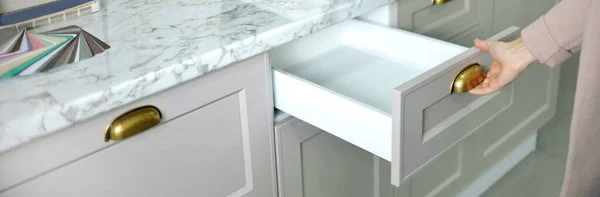 Banner Home geliştirme konsepti. Genç bayan tasarımcı bir mağazadaki mutfak dolabının çekmecesini açıyor.