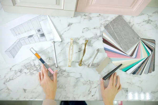 Ev geliştirme konsepti. Tasarımcı kız vitrindeki mobilyaların ön cephelerini ve kollarını seçiyor. Mobilya endüstrisinde dekorasyon tahtaları. Madde örnekleri seçiliyor.