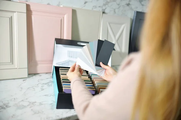 Kız tasarımcı kabine mobilyaları için ön cephe seçiyor. Mobilya endüstrisinde dekorasyon tahtaları. İç proje için malzeme ve renk örnekleri seçiliyor. Üst Görünüm Ev Geliştirme kavramı