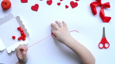 Sevgililer günü bilekliği için bebek kalemleri kırmızı boncuk kalpler dizer. El yapımı bebek dekorasyonu. El işi konsepti. Adım 3.Düzen, üst görünüm.