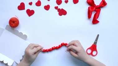 Sevgililer Günü için kırmızı boncuklu bilezikli bebek kalemleri. El yapımı bebek dekorasyonu. El işi konsepti. Adım 5. Düzen, üst görünüm.
