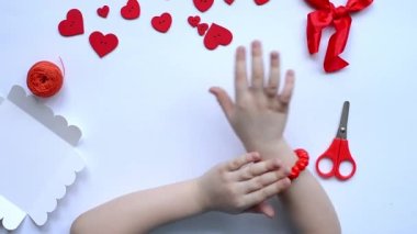 Sevgililer Günü 'nde bir kız için el yapımı kırmızı boncuk bileziği. El yapımı bebek dekorasyonu. El işi konsepti. Altıncı adım. Düzen, üst görünüm