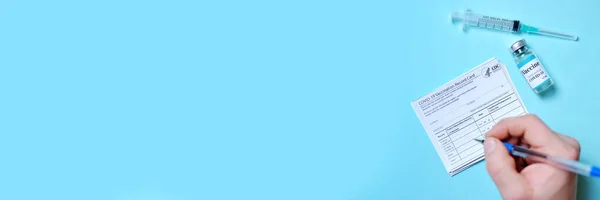 Bayrak doktorunun el yazısı aşı pasaportu dolduruyor. Dokunulmaz pasaport ya da seyahat konsepti sertifikası. 2019-ncov Covid-19 Corona Virüs Aşı İlaç Şişesi Şırınga Şırıngası.