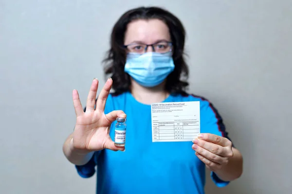 Kadının elinde aşı kayıtları ve Corona virüsü aşı şişeleri var. Ellerindeki koronavirüse karşı dokunulmazlık pasaportu. COVID-19 tedavisinin kanıtı olarak sağlık pasaportu