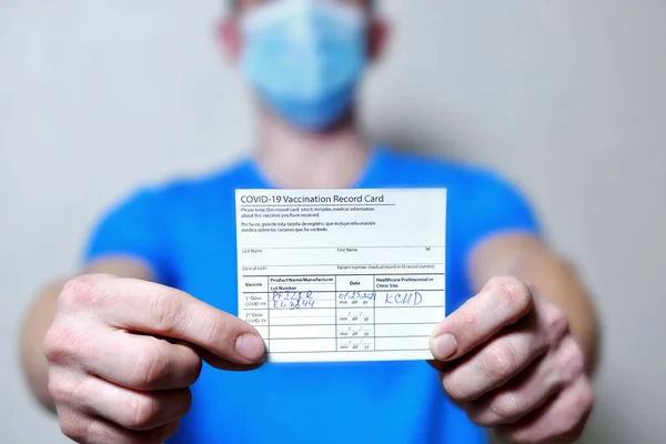 Erkek bir aşı kaydı tutuyor ve Corona virüsü aşı şişeleri. Koronavirüse karşı dokunulmazlık pasaportu bir erkeğin elinde. COVID-19 tedavisinin kanıtı olarak sağlık pasaportu