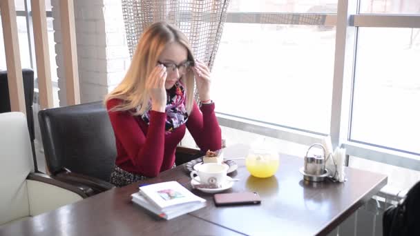 Νεαρή Επιτυχημένη Κοπέλα Χωρίς Μάσκα Διαβάζει Ένα Βιβλίο Ένα Καφέ — Αρχείο Βίντεο