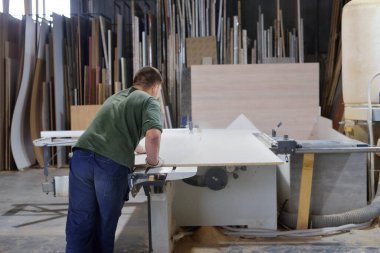 Kendi küçük başarılı üretim kavramı. Marangoz atölyesinde mobilya yapmak için testere makinesi kullanan bir işçi. Küçük mobilya fabrikasında el yapımı iş.