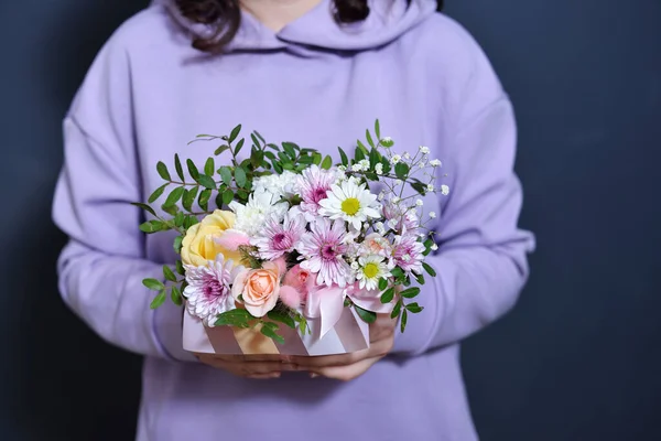 Mor kazaklı esmer bir kız elinde bir buket tutuyor..