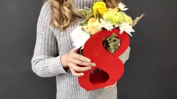 一个穿着灰色毛衣的金发女孩手里拿着一束花在八号录像里 国际妇女日礼物 — 图库视频影像
