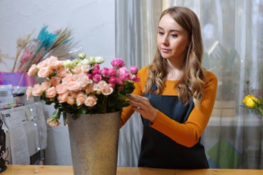 Çiçekçi kadın buket için gülleri seçiyor. Çiçek demeti, eve gitmek için hazır. Dekorasyon için taze kesilmiş çiçekler. Avrupa çiçekçisi. Taze kesilmiş çiçek getirdim.