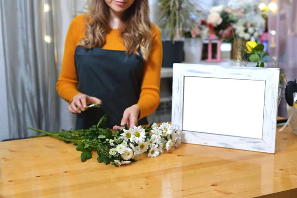 florist girl in an apron to work on creating a creative bouquet for a client. online order preparation concept. Space for text