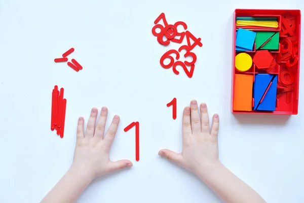 Çocuk sayı doğrusunu ve geometrik şekilleri öğreniyor. Anaokulu öğrencisi Montessori malzemeleriyle çalışıyor. Çocuklar için eğitici mantık oyuncakları. Çocukların elleri, yakın plan. Çocuk Gelişimi için Montessori Oyunları.