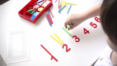 Çocuk sayı doğrusunu ve geometrik şekilleri öğreniyor. Anaokulu öğrencisi Montessori malzemeleriyle çalışıyor. Çocuklar için eğitici mantık oyuncakları. Çocukların elleri, yakın plan. Çocuk Gelişimi için Montessori Oyunları.