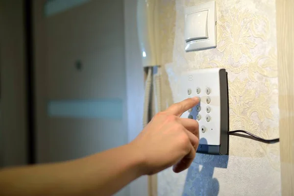 Adamın eli, evdeki güvenlik sisteminden gelen kodu hırsızlık ve hırsızlıktan kalma numaralarla tuşluyor. Lastik ve hırsıza karşı izleme ve koruma konsolu.