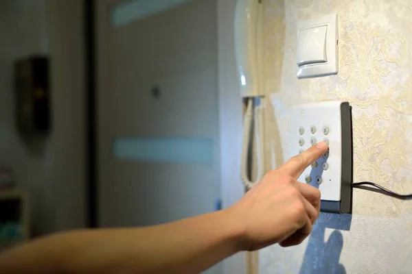 Adamın eli, evdeki güvenlik sisteminden gelen kodu hırsızlık ve hırsızlıktan kalma numaralarla tuşluyor. Lastik ve hırsıza karşı izleme ve koruma konsolu.