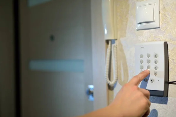 Adamın eli, evdeki güvenlik sisteminden gelen kodu hırsızlık ve hırsızlıktan kalma numaralarla tuşluyor. Lastik ve hırsıza karşı izleme ve koruma konsolu.