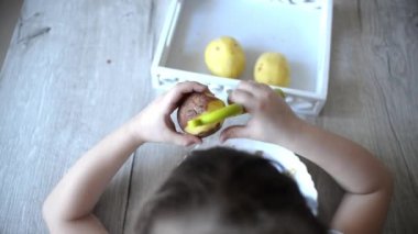 Pratik yaşam alanından ders almak için patatesleri montessori malzemesiyle soyan çocukların elleri. Soyucu, patates, tabak, tepsi. Evdeki yaşam tarzı