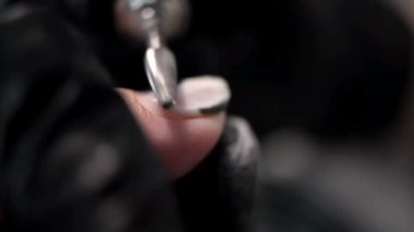 Manikürcü siyah eldiven giyerek tırnak tabağındaki eski kaplamayı kaldırıyor. Kendine özen gösterme. Güzellik konsepti profesyonel tırnak bakımı.