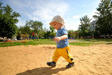 Küçük çocuk mutlu bir şekilde koşuyor ve oyun bahçesinde oynuyor. Spor yaşam tarzı konsepti. Temiz havada yürü. Çocuklar yazın oyun bahçesinde oynarlar.