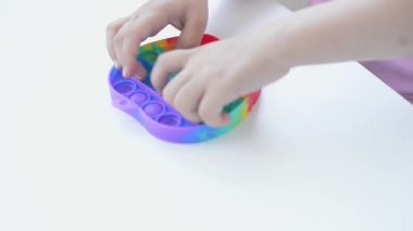 Pembe tişörtlü bir kız son moda bir oyuncakla oynuyor. Renkli stres önleyici oyuncaklar. Çocuğun eline tak, otistik insanlarla eğitim için kullanılabilir.