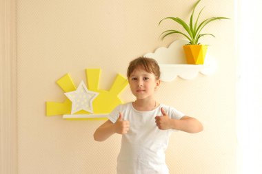 Şık ve modern iç tasarım. Kız bebek odasındaki yeni raflarda mutlu bir hayat sürüyor. Çocukların rafları bej bir duvarda beyaz bulutlar şeklinde, üzerinde çiçek olan sarı bir tencere var..