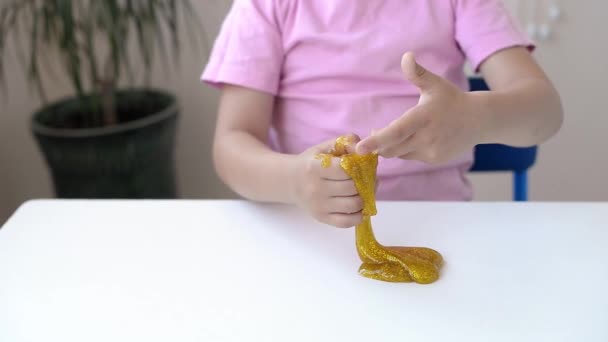 Menina Rosa Shirt Segurar Alongamento Lodo Amarelo Com Tranças Douradas — Vídeo de Stock